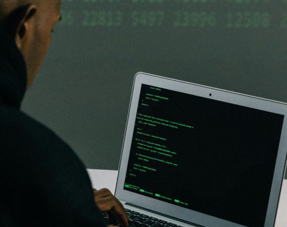 IT professional coding on a desktop computer, working on IoT-Enabled VoIP Security configurations for a business communication system.