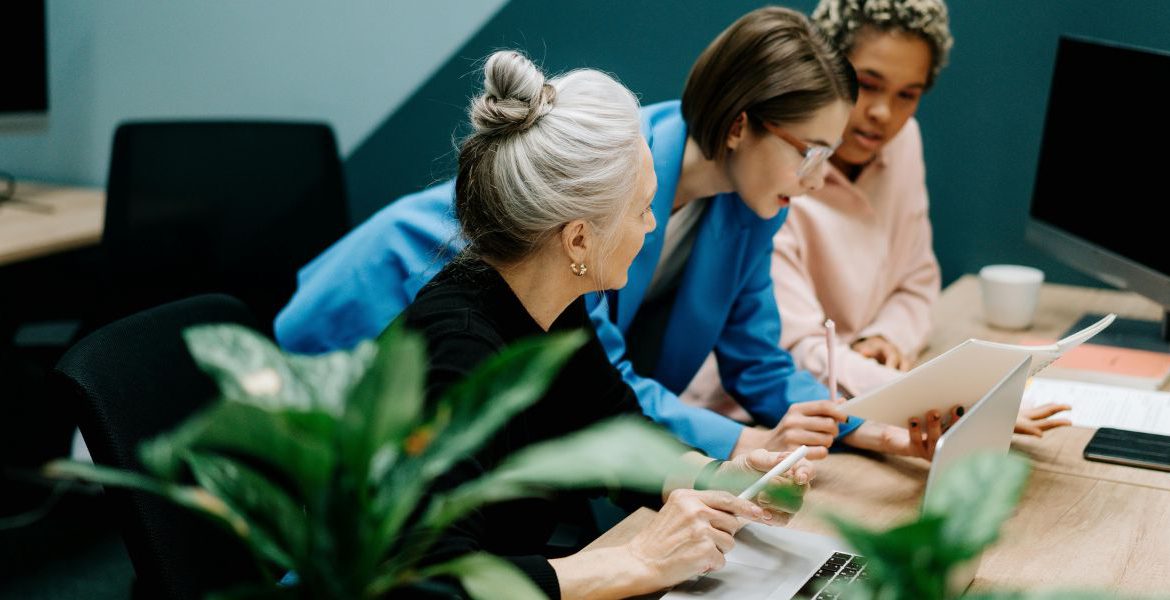 Three women in a strategic meeting discussing a VoIP and IoT business strategy in a modern office setting.