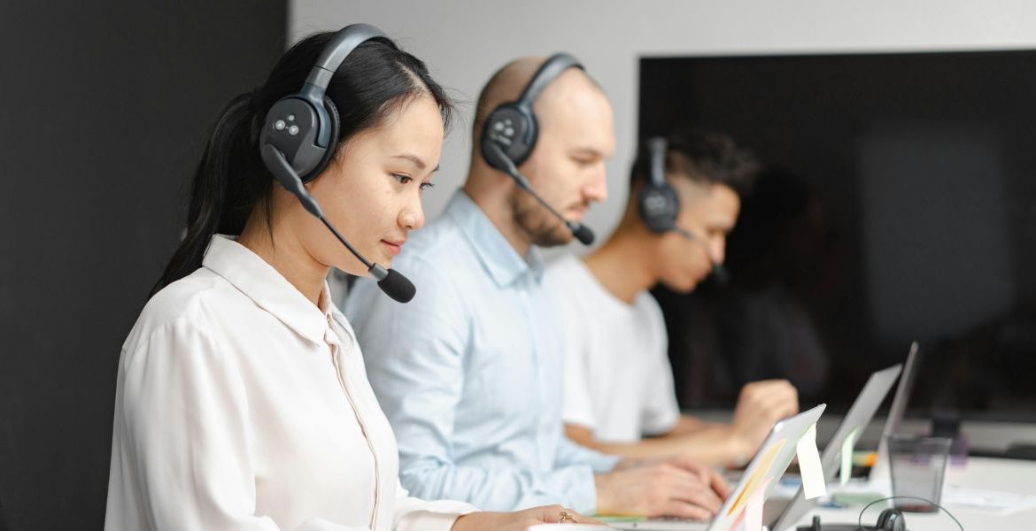 Team using headsets and computers to manage smart systems, showcasing VoIP and IoT implementation guide in a modern business setting.