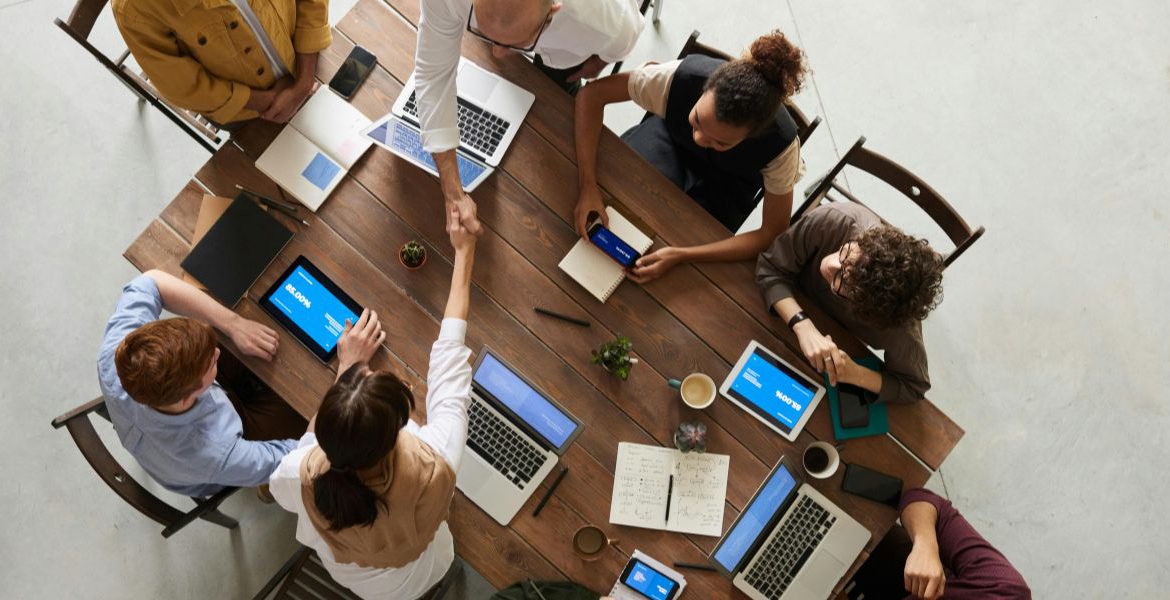 Business professionals shaking hands during a team meeting, representing successful VoIP and IoT integration in a modern workplace.