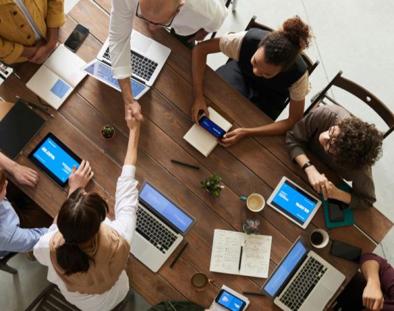 Business professionals shaking hands during a team meeting, representing successful VoIP and IoT integration in a modern workplace.