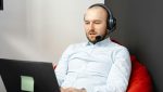 Man using VoIP on a laptop with a headset, benefiting from VoIP Quality of Service (QoS) for clear and reliable communication.