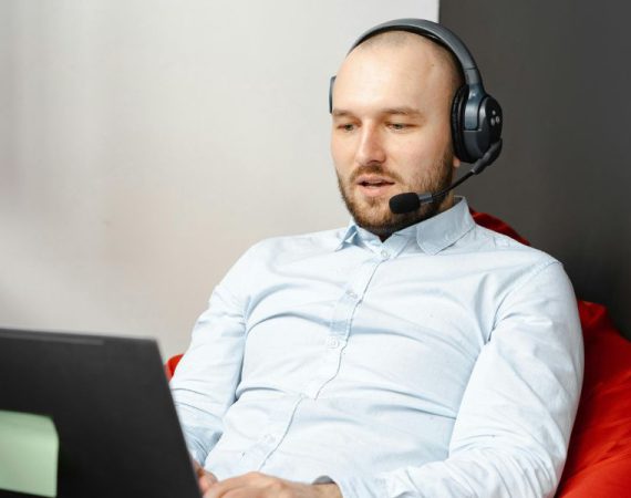 Man using VoIP on a laptop with a headset, benefiting from VoIP Quality of Service (QoS) for clear and reliable communication.